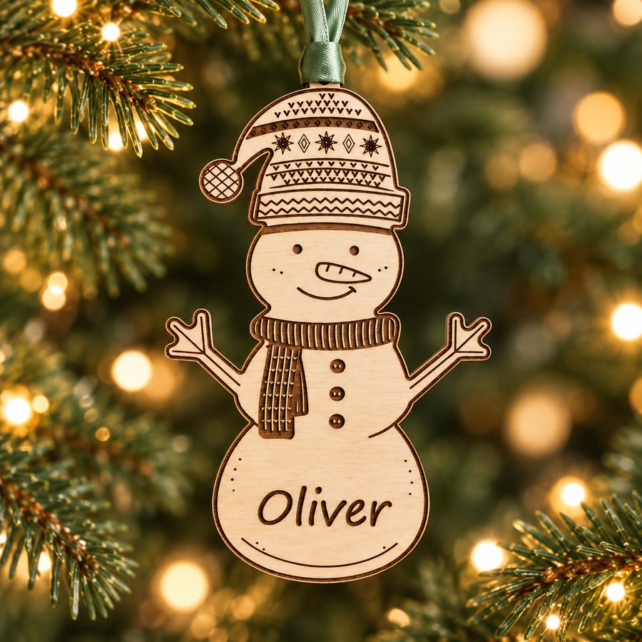 Personalised wooden snowman bauble engraved Oliver, hanging on a Christmas tree with sage green ribbon.