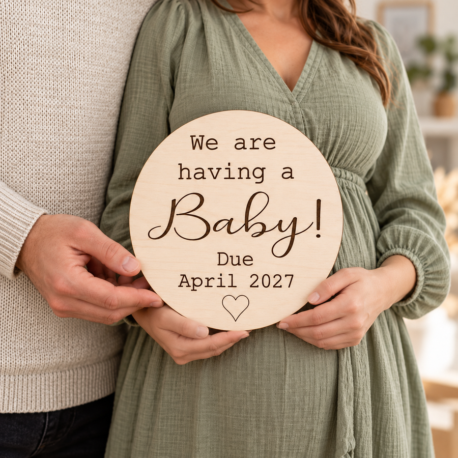 Expectant couple holding a round We are having a Baby sign with dark engraving and personalised due date