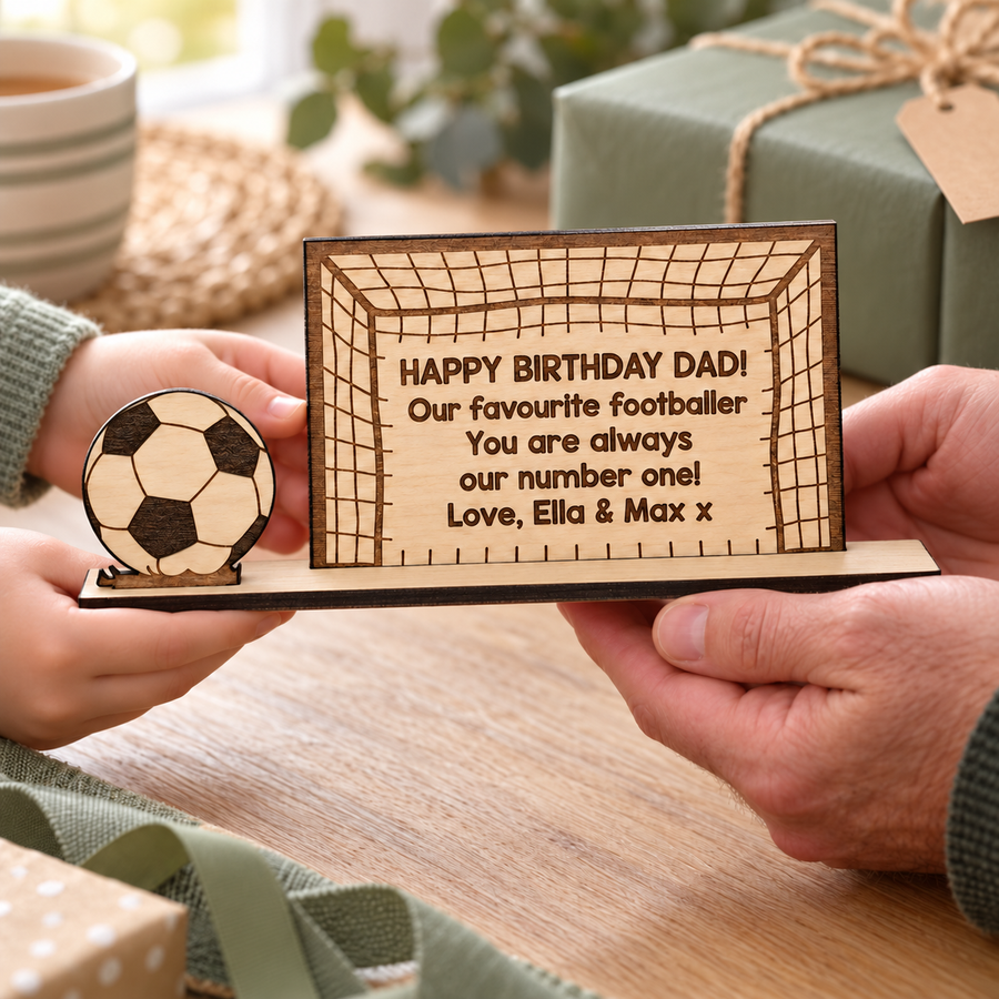 Child giving Dad a personalised football birthday keepsake with a custom message and dark engraved football.