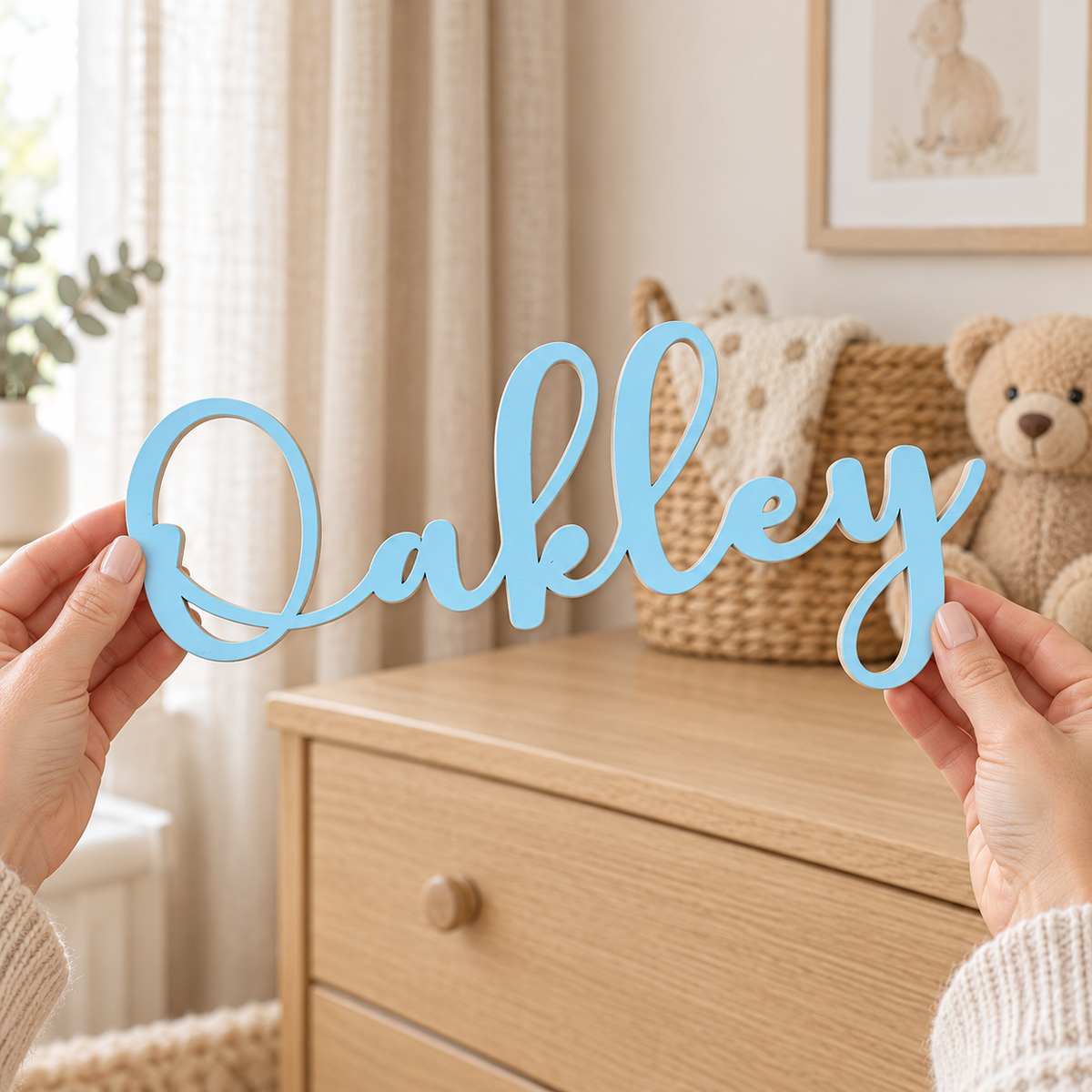 Pastel blue Oakley name cut from thin birch plywood, held in adult hands to show the lettering and finish