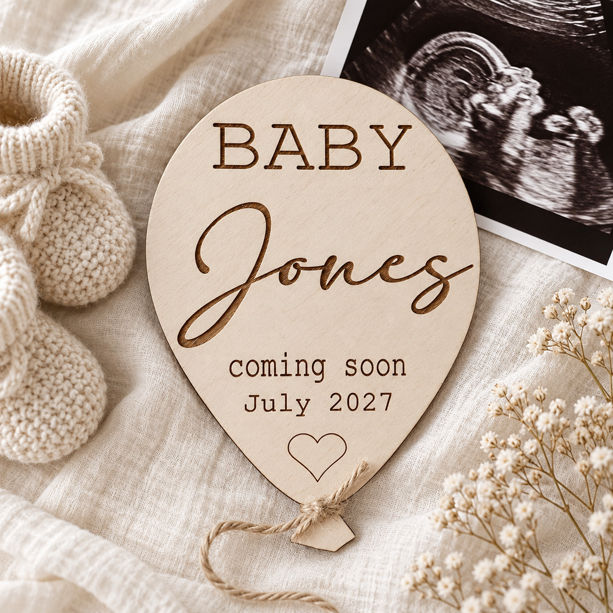 Baby Jones coming soon balloon plaque beside ultrasound photo and cream knitted booties