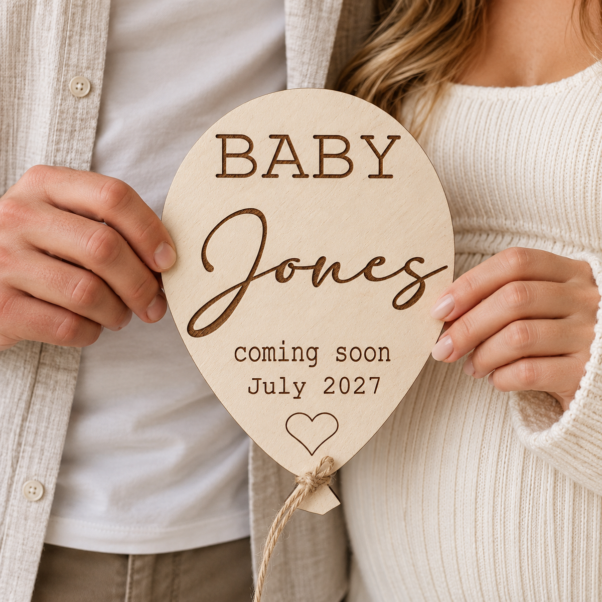Couple holding personalised Baby Jones coming soon wooden balloon for pregnancy reveal