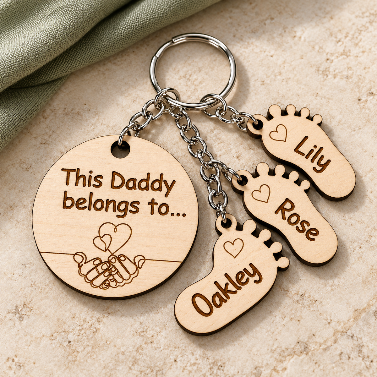 Full wooden Daddy keyring with silver split ring, linked hands and hearts design, and Oakley, Rose and Lily footprint charms.
