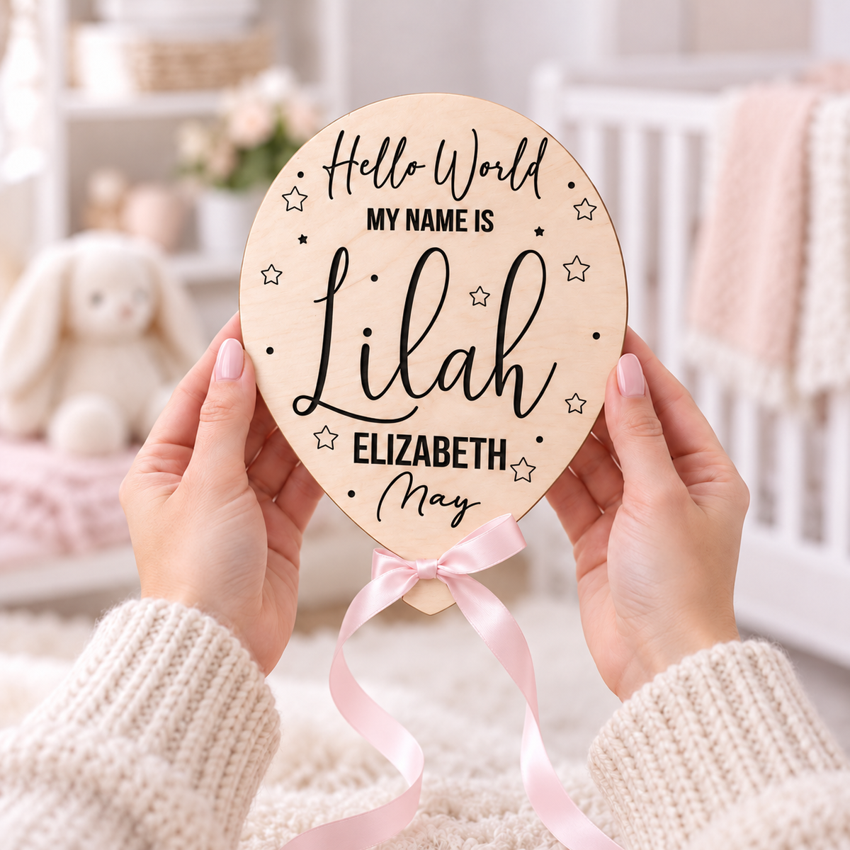 Pink ribbon Hello World name reveal balloon held in adult hands