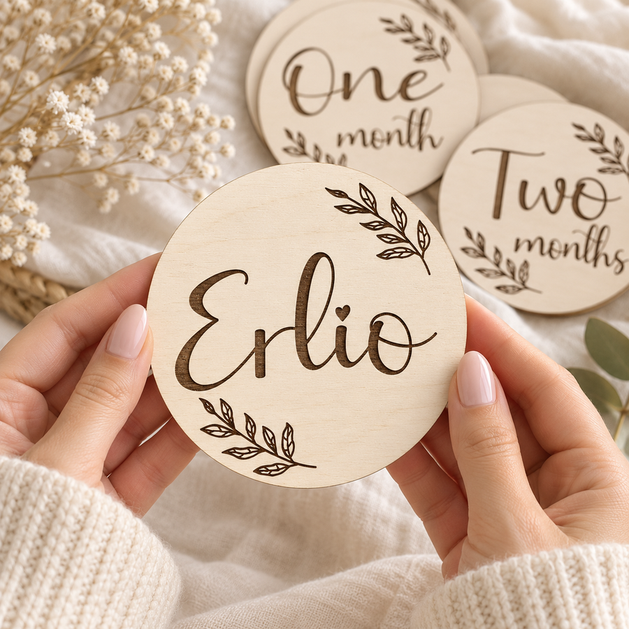 Personalised baby milestone name card held in hands with botanical engraving and monthly cards behind
