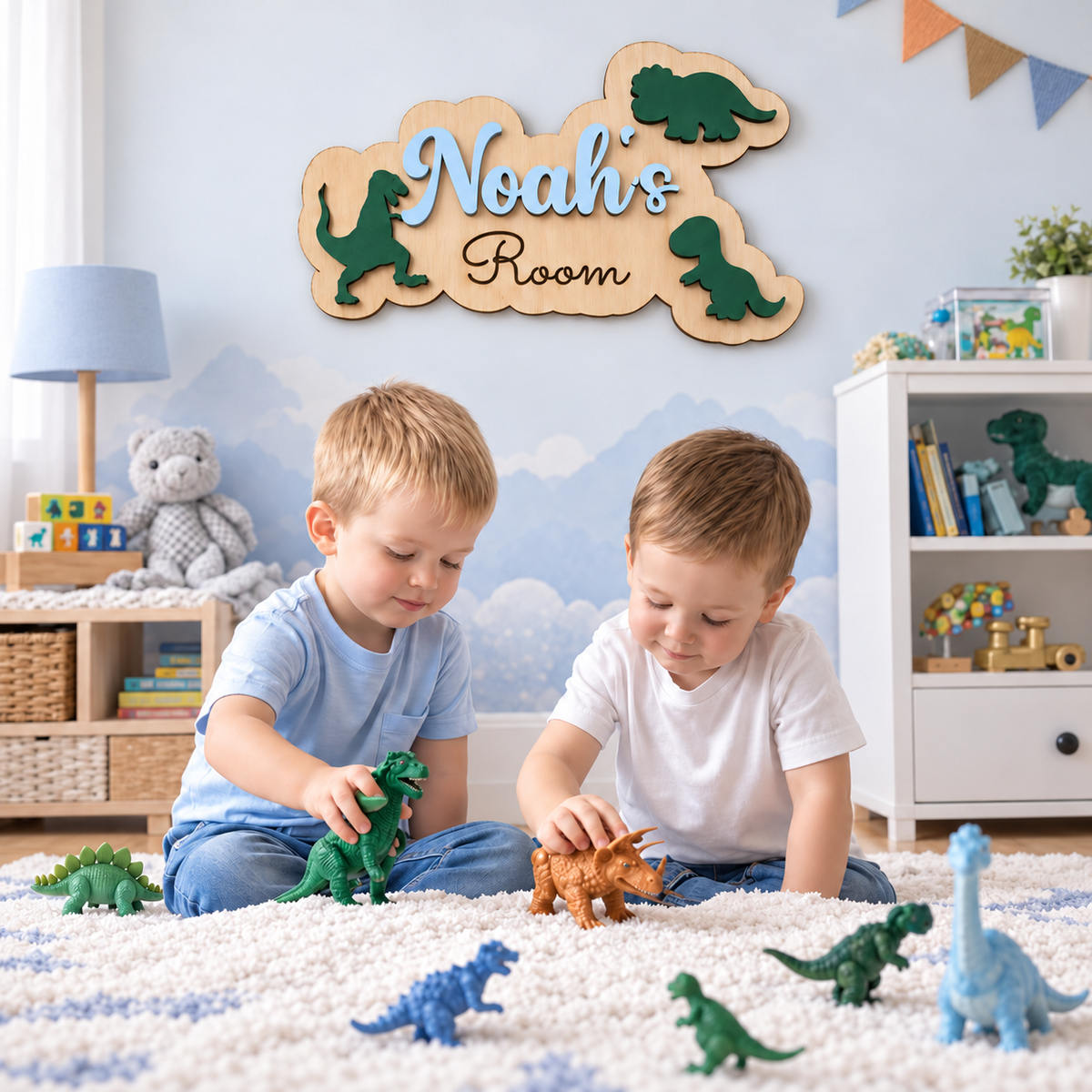 Pastel blue Noah's Room dinosaur name sign on a nursery wall above two children playing with dinosaur toys.