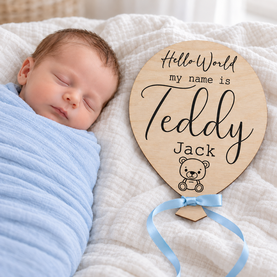 Engraved baby name plaque with Teddy Jack, teddy bear detail and blue ribbon beside a sleeping newborn