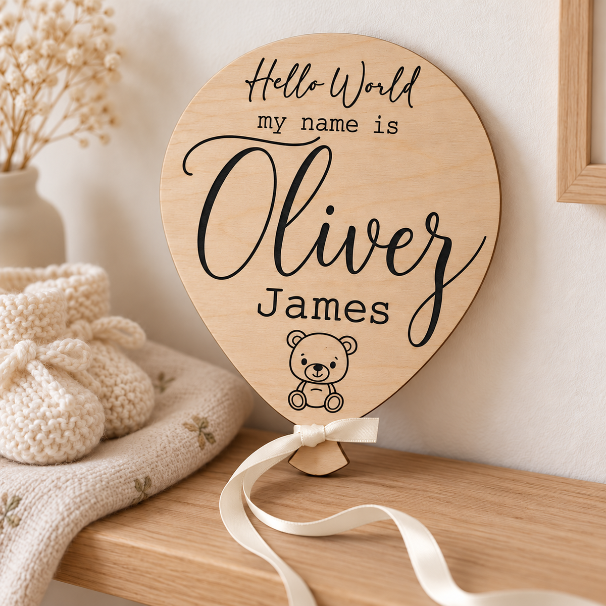 Oliver James engraved baby name keepsake with cream ribbon on a nursery shelf