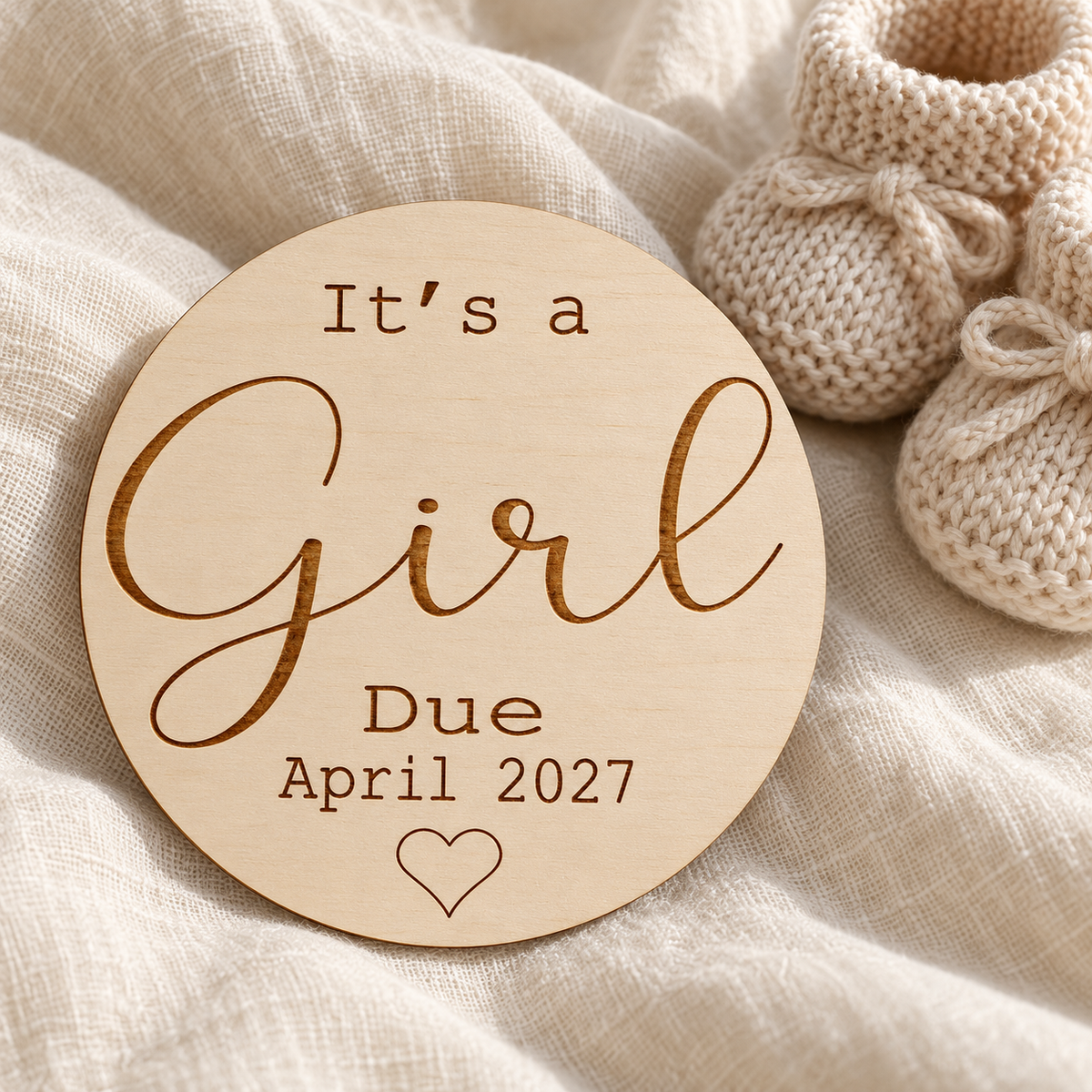 It's a Girl pregnancy reveal photo prop beside neutral knitted baby booties