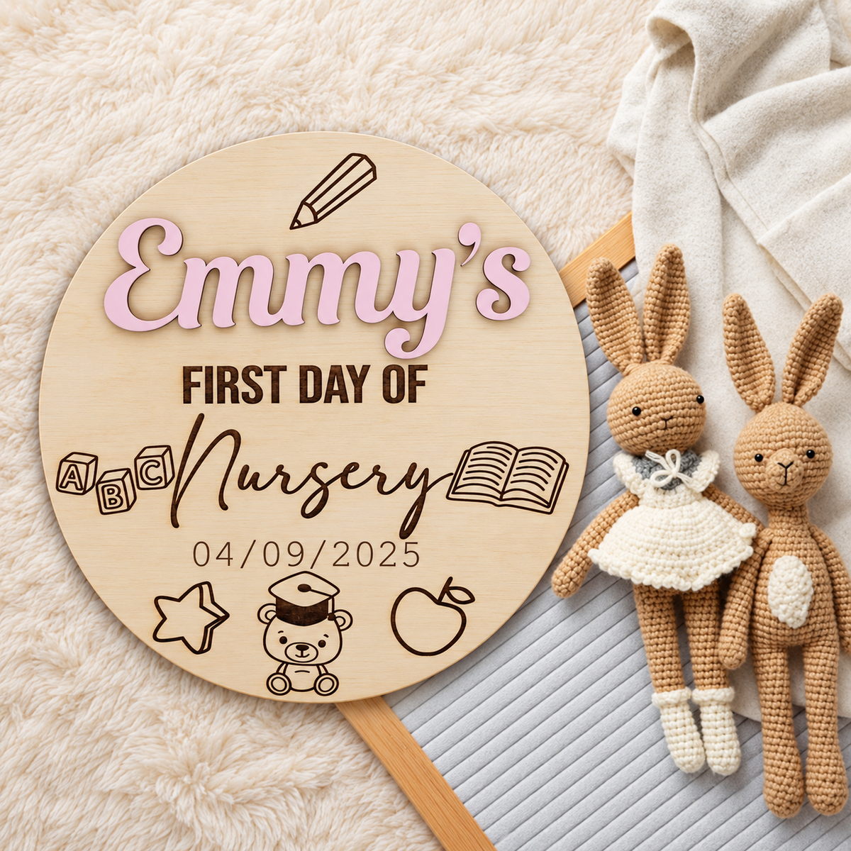 Emmy's personalised first day of nursery plaque with raised pastel pink name beside crocheted rabbits