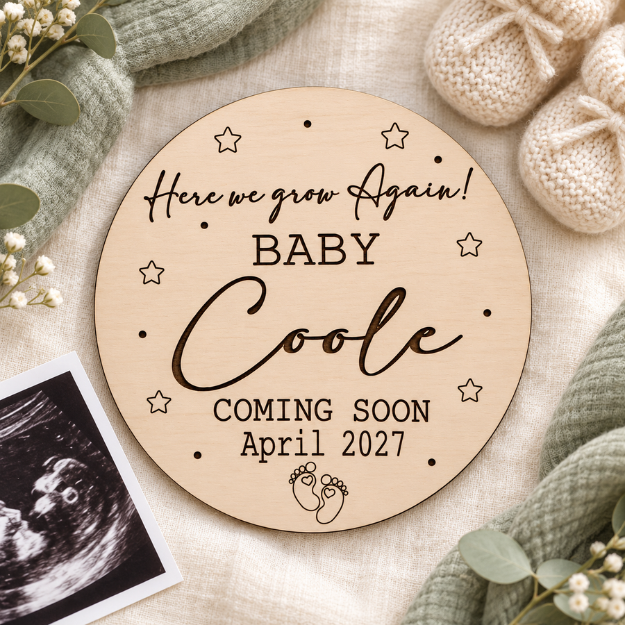Here We Grow Again baby Coole sign with April 2027 due date beside cream baby booties