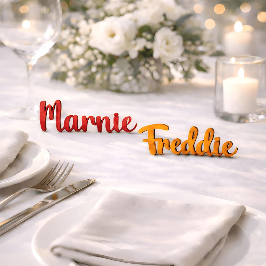 Wedding table setting with wooden name place cards reading “Marnie” and “Freddie”, with candles and white flowers.