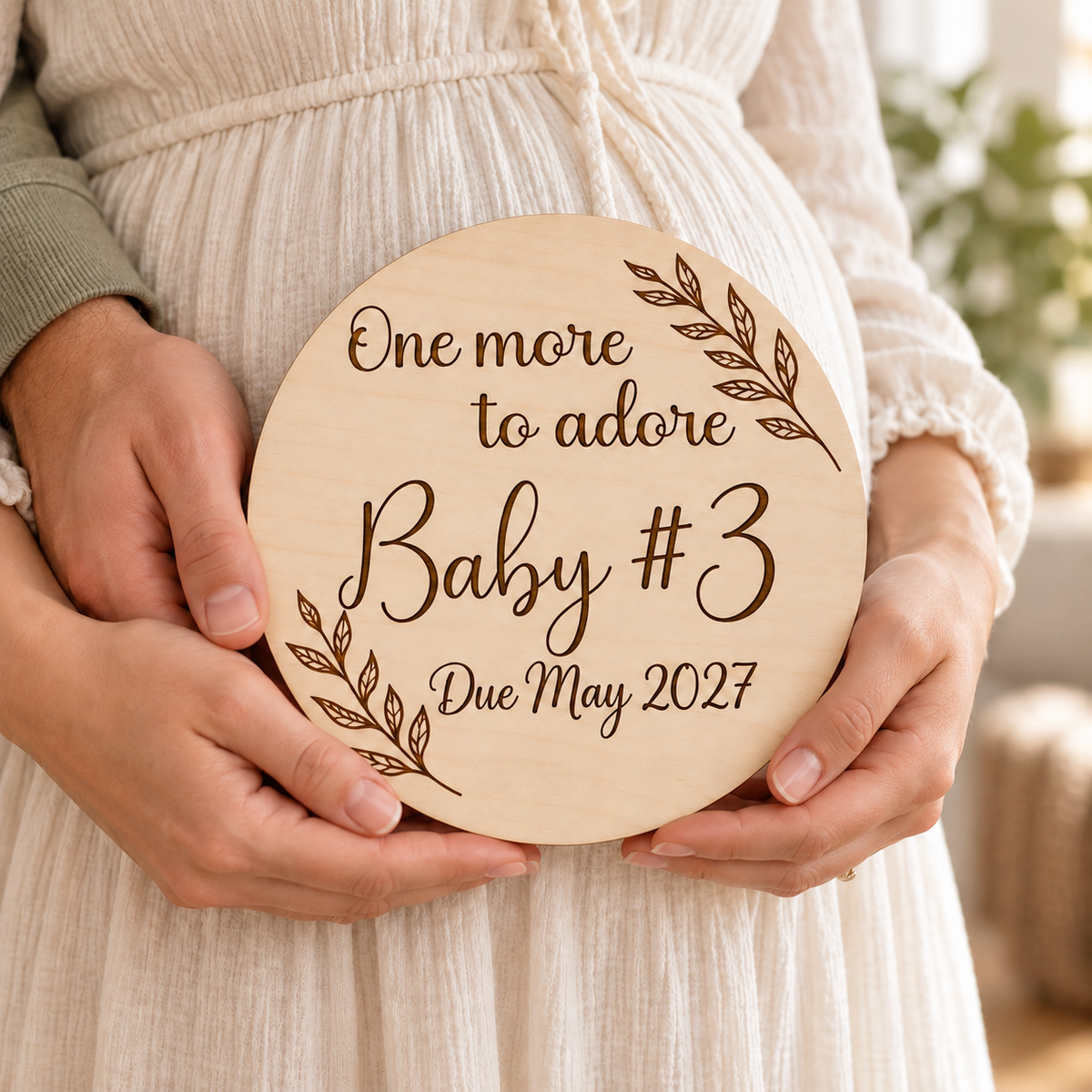 Expectant parents holding a personalised Baby #3 announcement plaque