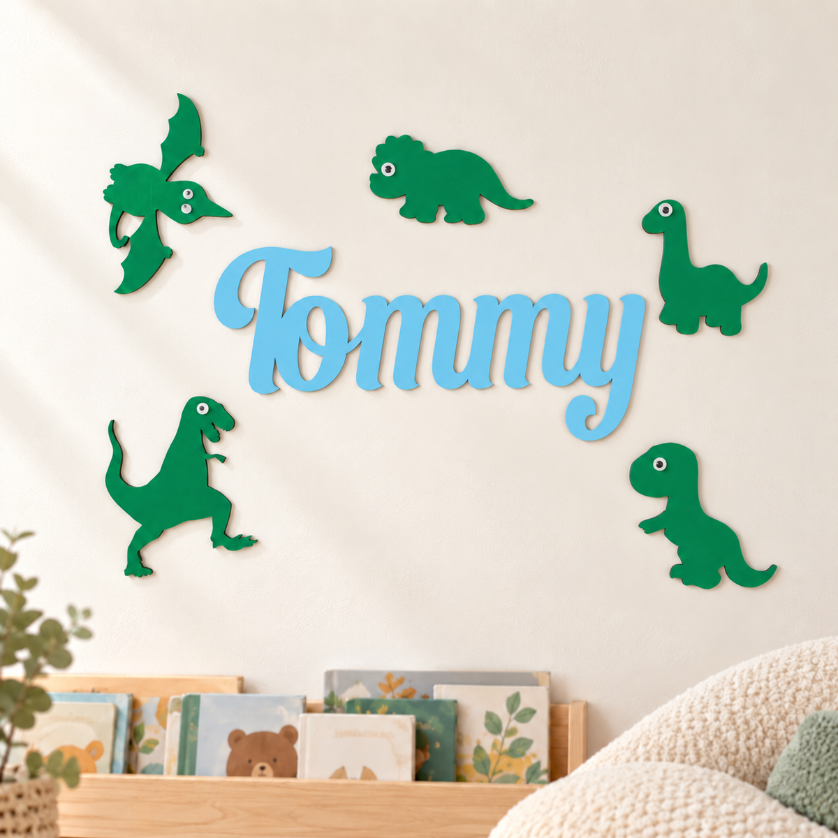 Close-up of the connected pastel blue Tommy wooden name with five green dinosaur wall decorations