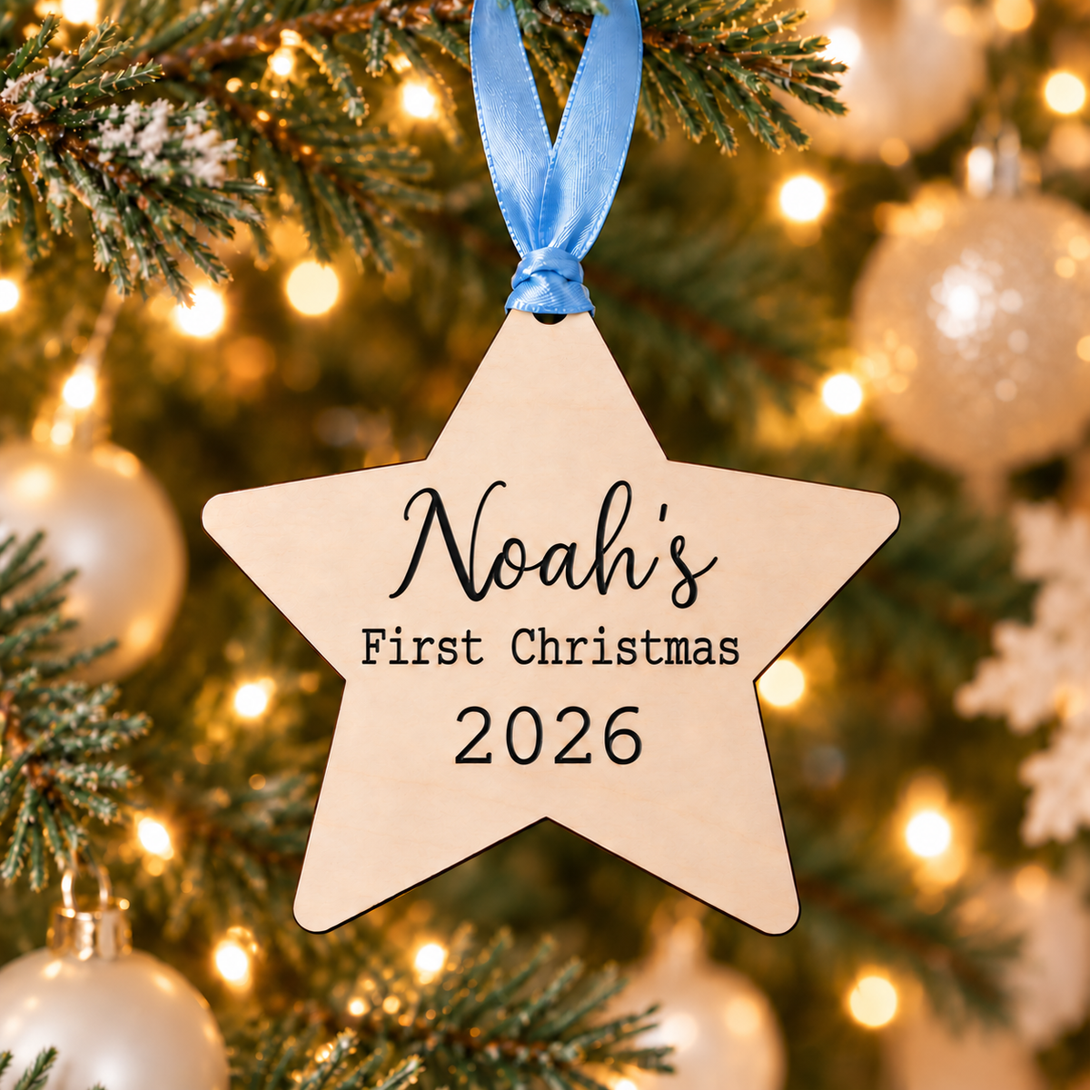 Noah's first Christmas wooden star ornament with black engraving, blue ribbon and 2026, hanging on a Christmas tree