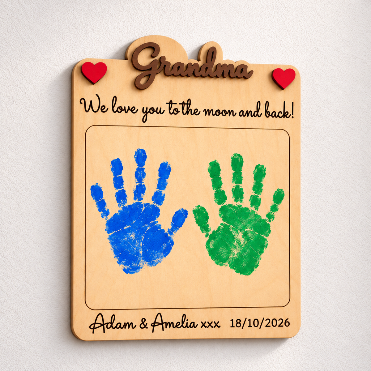 Personalised Grandma wooden handprint gift with brown raised lettering, blue and green handprints and names engraved below.