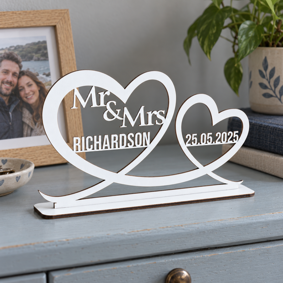 White personalised Mr and Mrs heart ornament with Richardson surname and wedding date on a blue dresser beside a couple photo