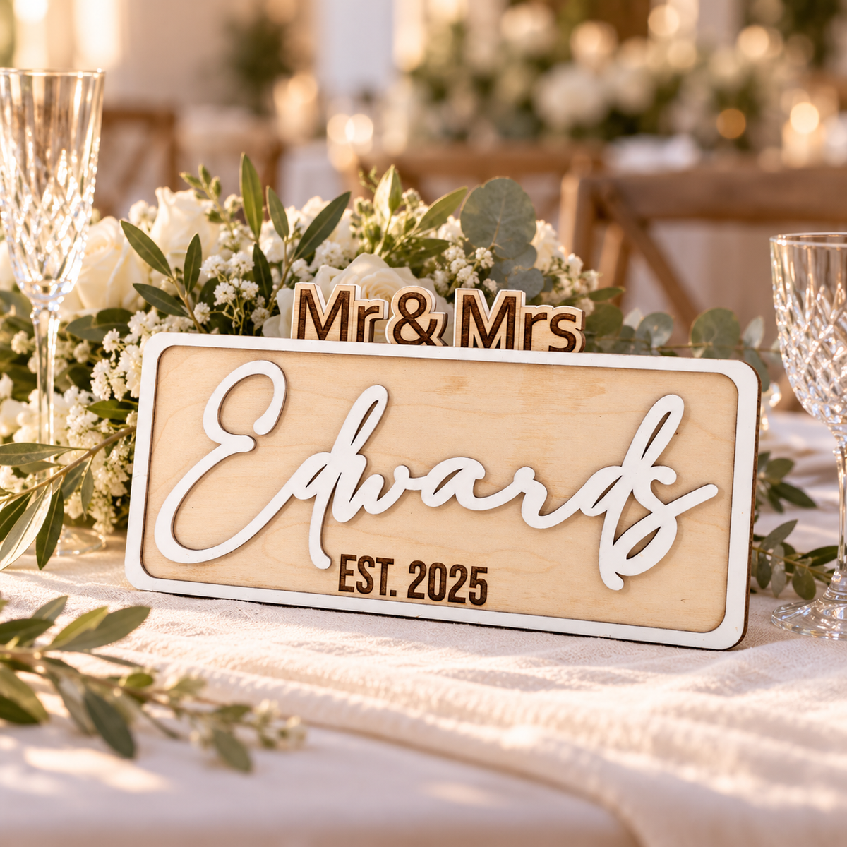 White personalised Mr & Mrs surname sign styled on a wedding table with flowers