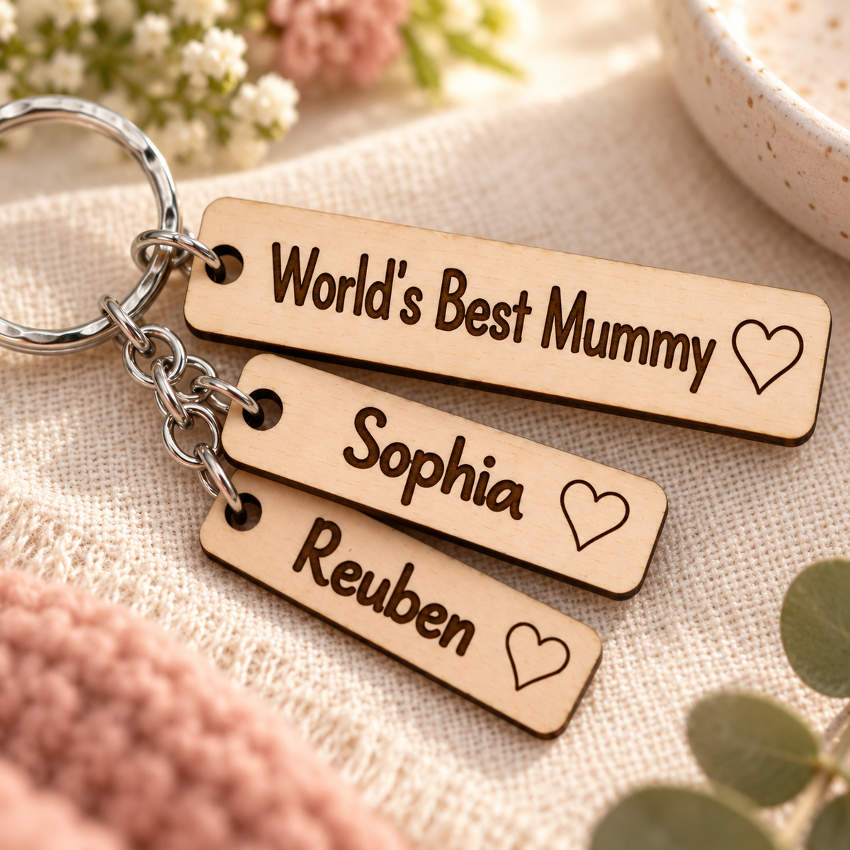 Close-up of bold dark laser engraving on the World's Best Mummy tag and Sophia and Reuben name charms.