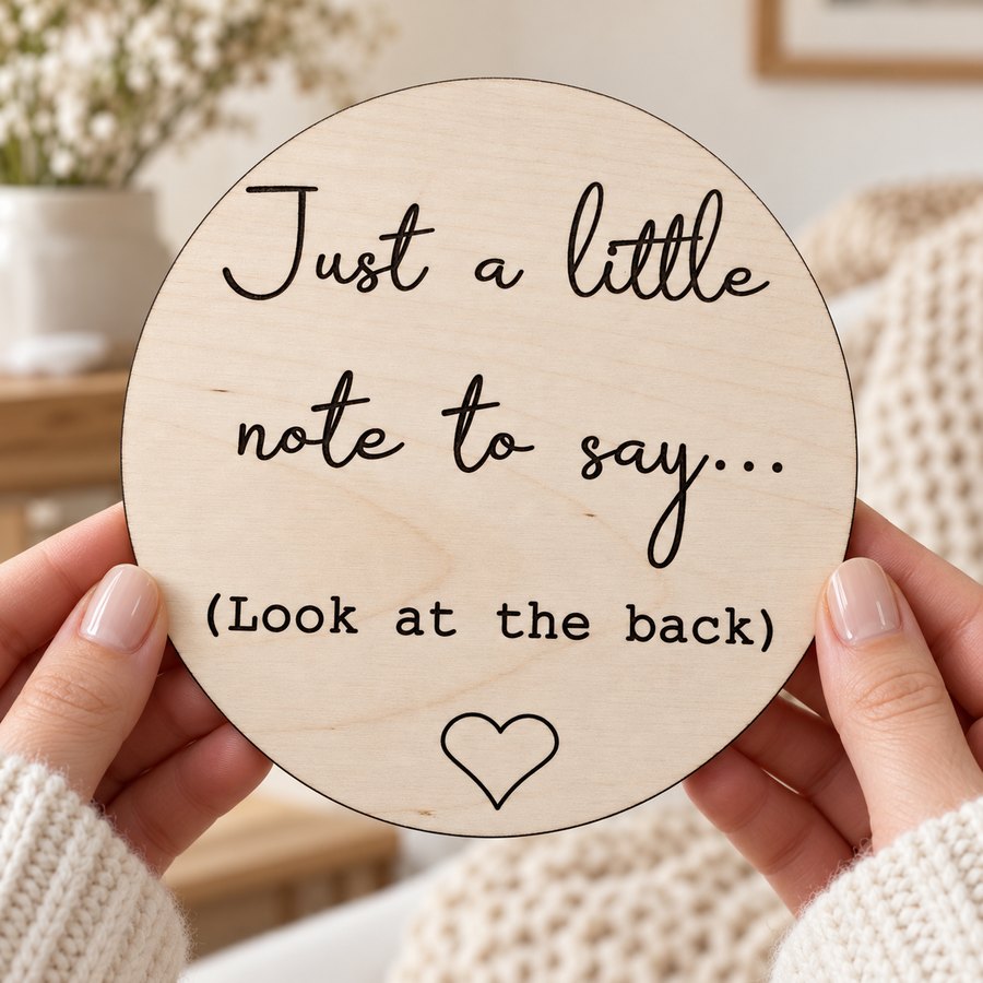 Front of the wooden announcement disc held in hands, engraved Just a little note to say and Look at the back