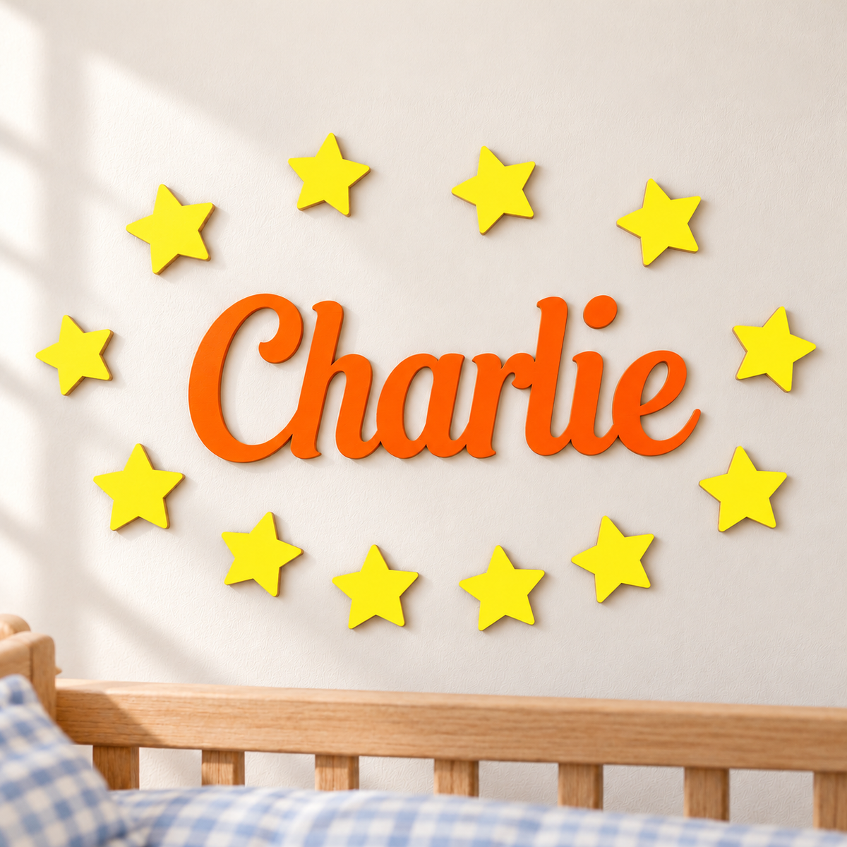 Orange personalised wooden name Charlie with 12 bright yellow stars on a bedroom wall