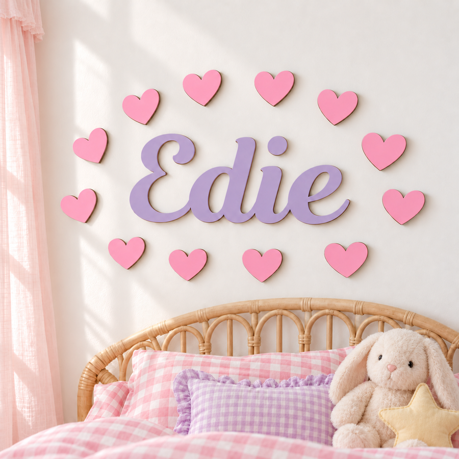 Lilac personalised wooden name sign Edie with 12 pastel pink hearts above a child's rattan bed