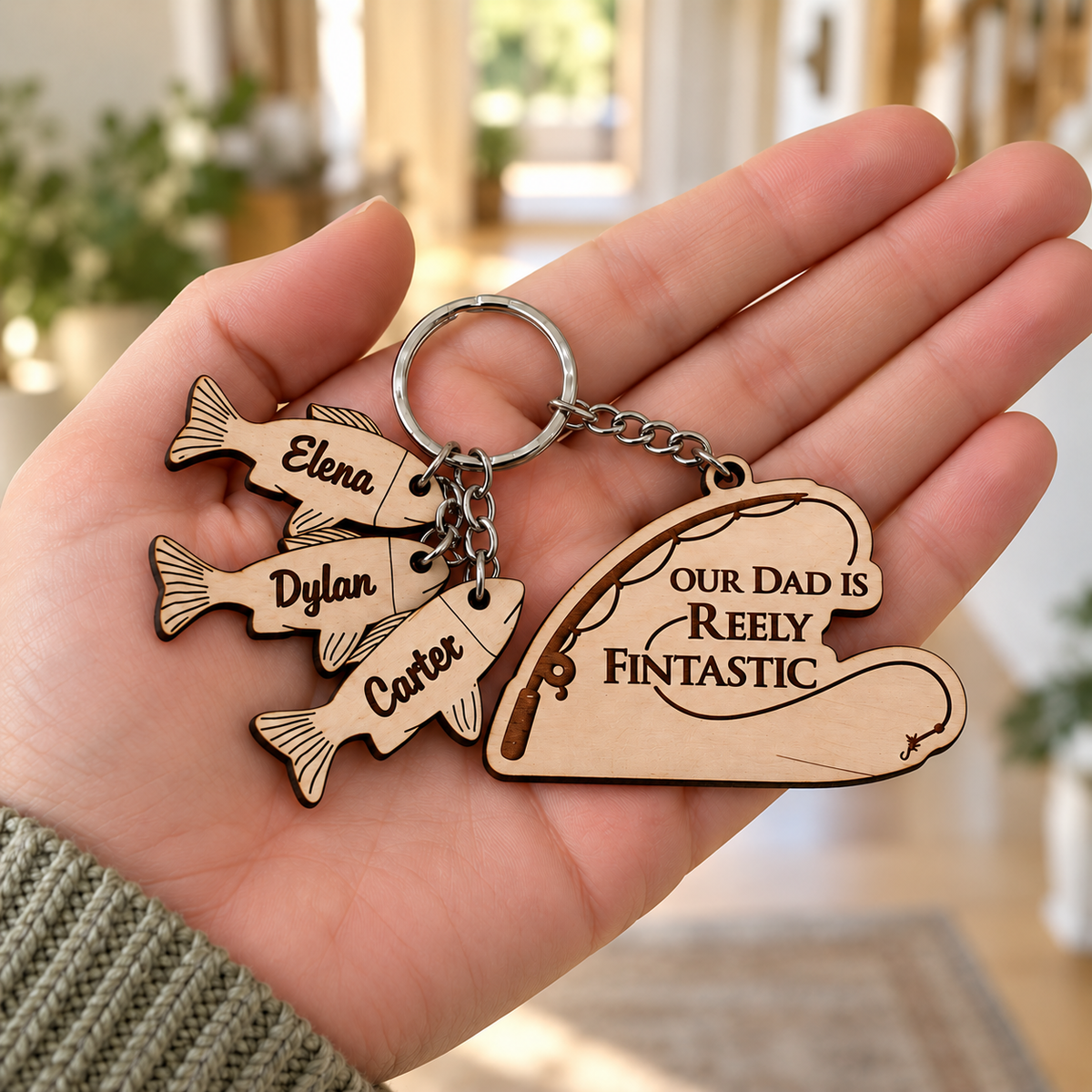 Reely Fintastic wooden fishing keyring with three engraved named fish charms held in an adult hand