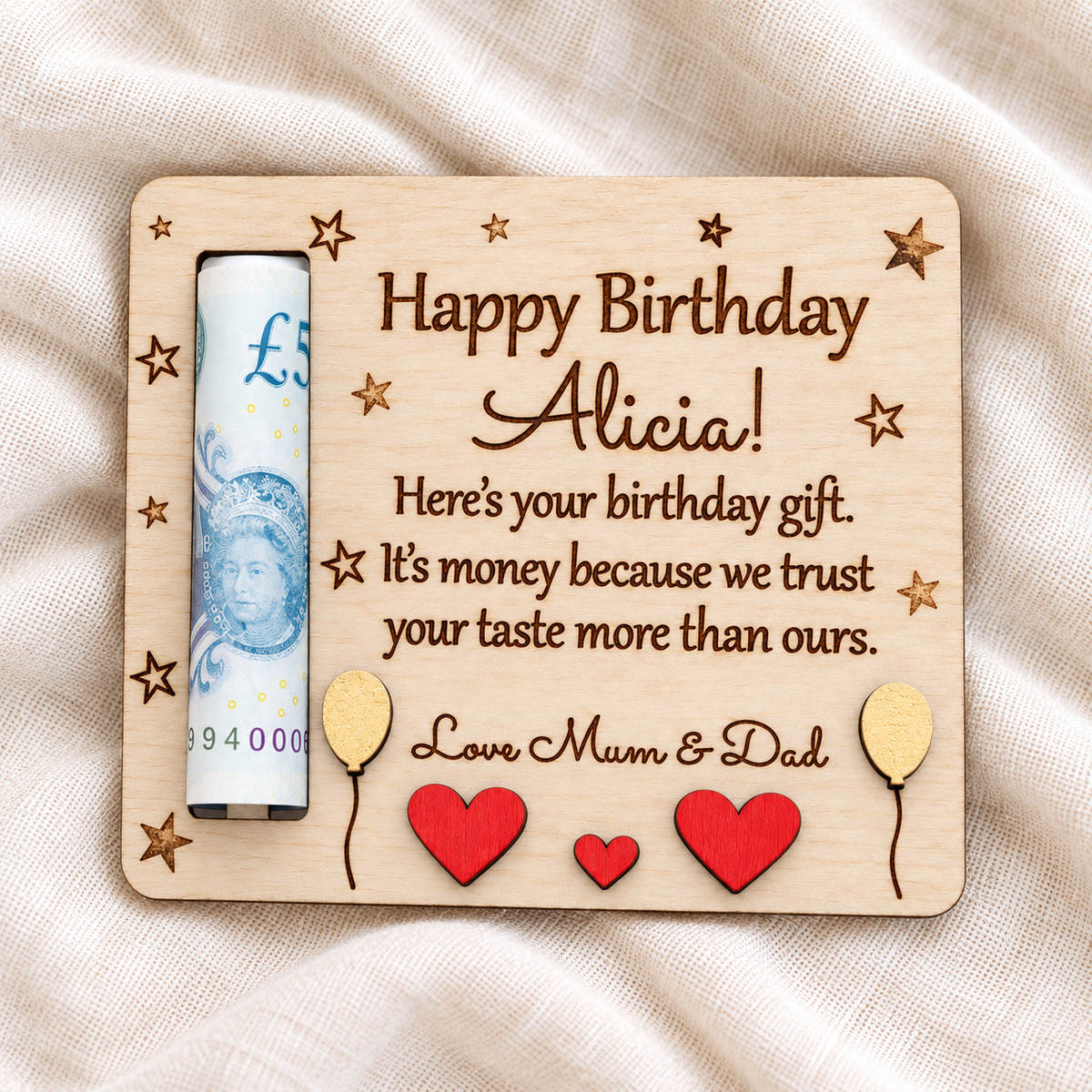 Alicia's wooden birthday cash gift card on ivory linen, showing the personalised greeting, Love Mum and Dad sign-off and raised wooden decorations