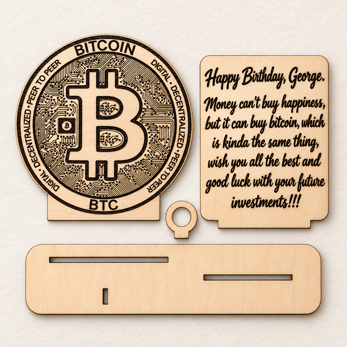 Four wooden Bitcoin gift components laid flat: engraved disc, message plaque, slotted base and banknote holder ring