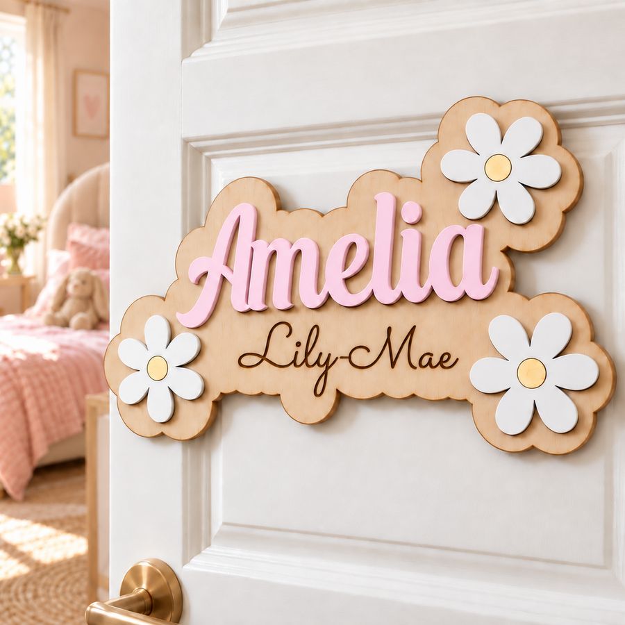 Pastel pink Amelia wooden name sign with Lily-Mae engraved below and white daisies, displayed on a bedroom door.