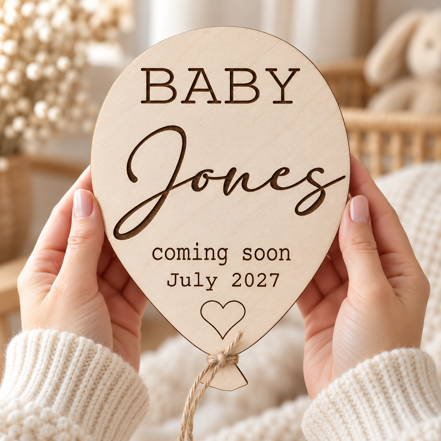 Baby Coming Soon wooden balloon sign held in hands, engraved Baby Jones and July 2027