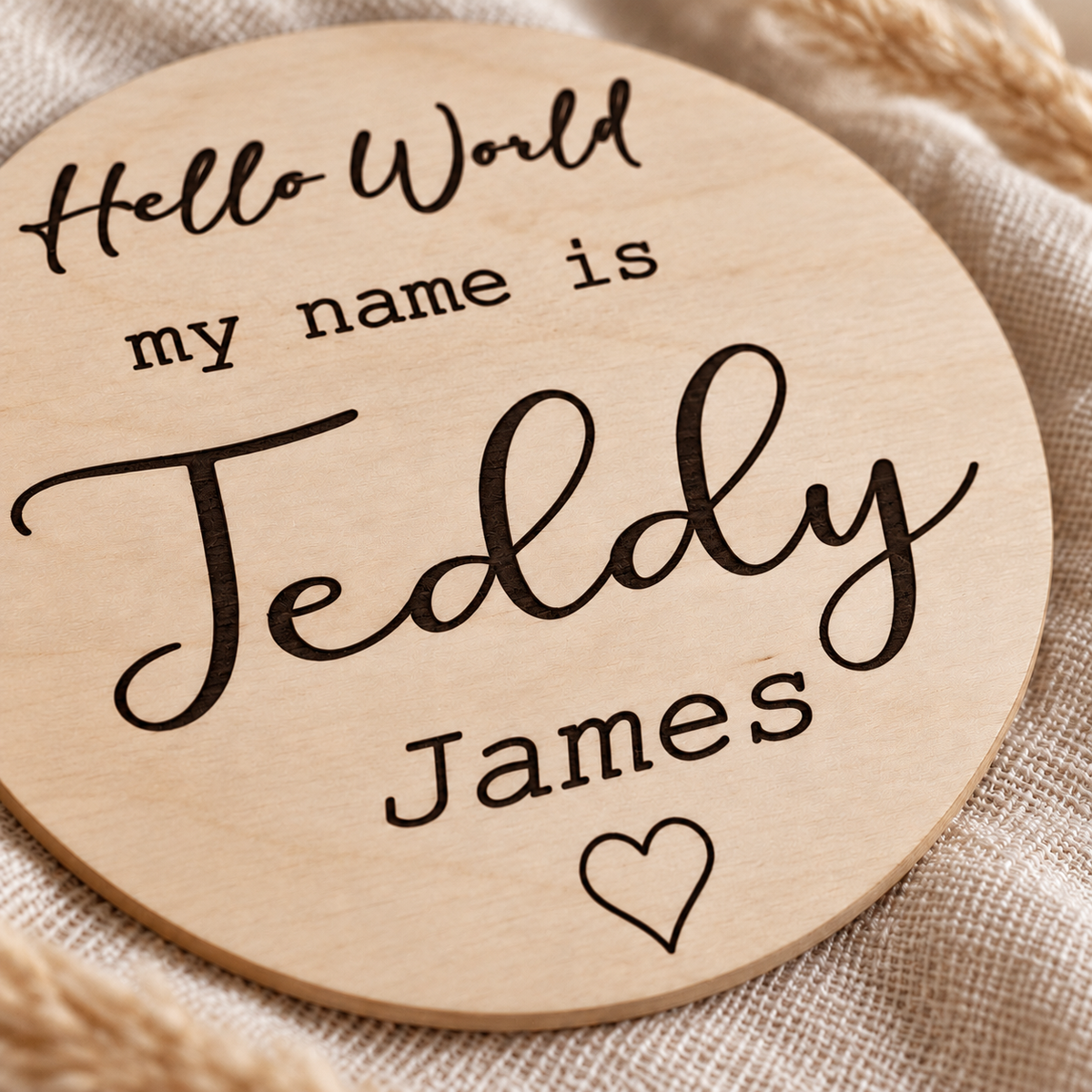 Close-up of dark engraved Teddy James lettering and outline heart on natural birch plywood