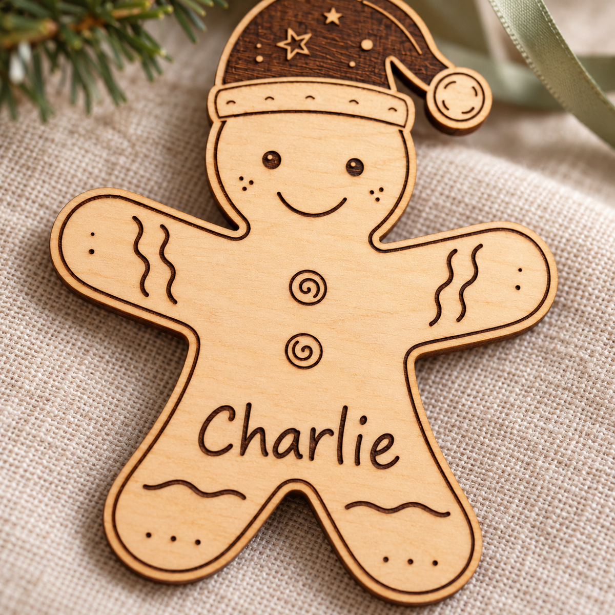 Close-up of Charlie engraved into a wooden gingerbread ornament with spiral buttons and fine natural birch grain