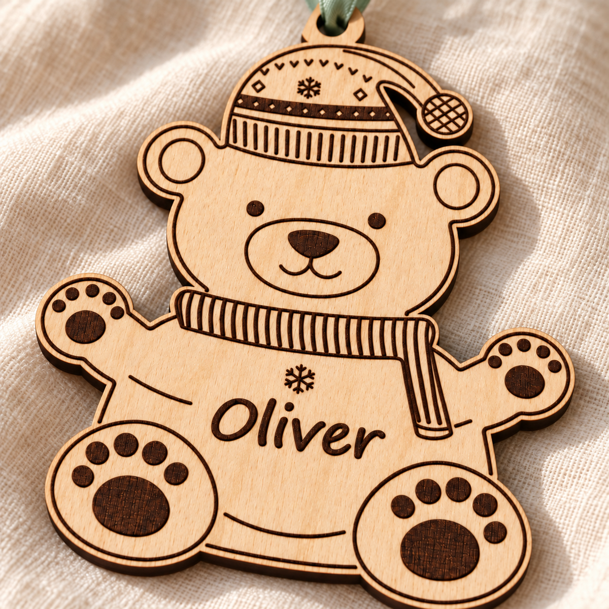 Close-up of the Oliver name, winter scarf and paw details engraved into the birch plywood polar bear Christmas ornament.