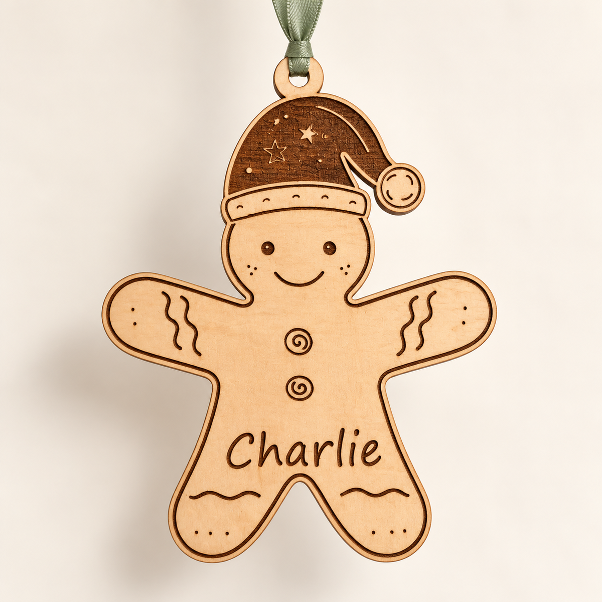 Full wooden gingerbread man Christmas decoration with engraved name and sage green ribbon against an ivory background