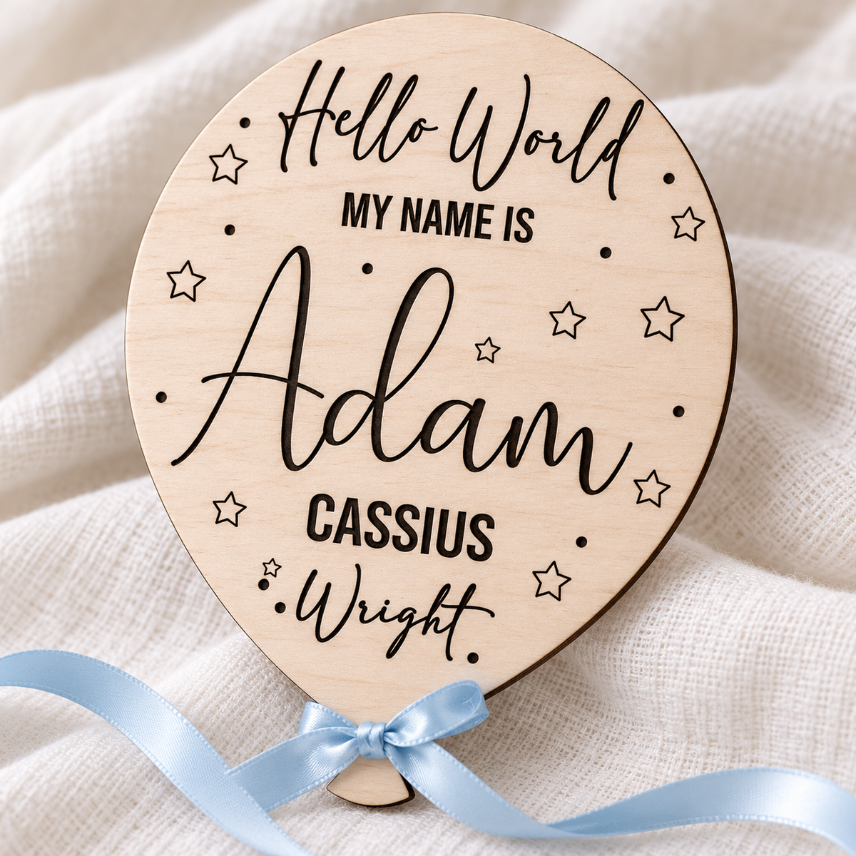 Close-up of dark engraved names, Hello World lettering and stars on birch plywood