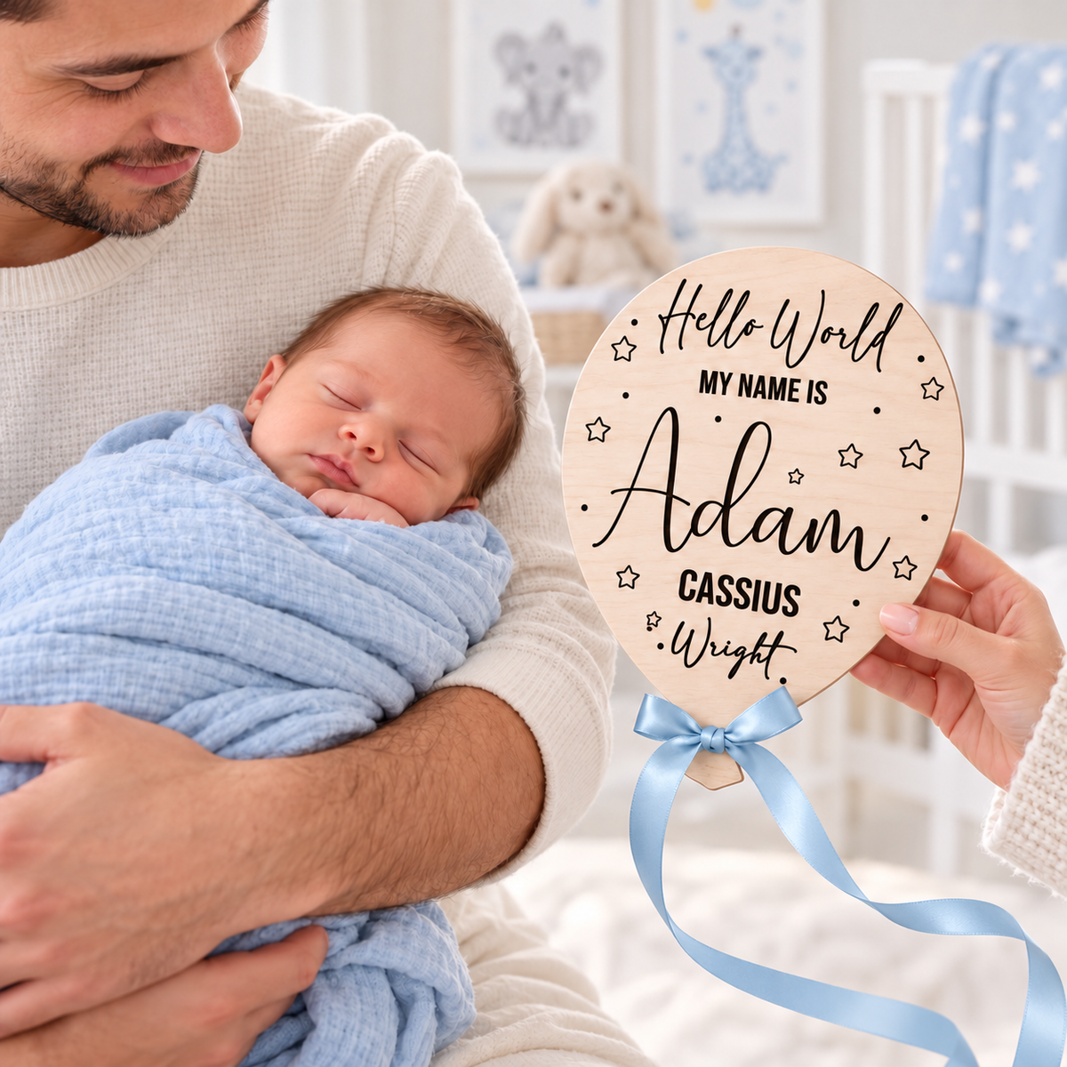 Blue ribbon engraved baby name balloon beside a newborn held by a parent