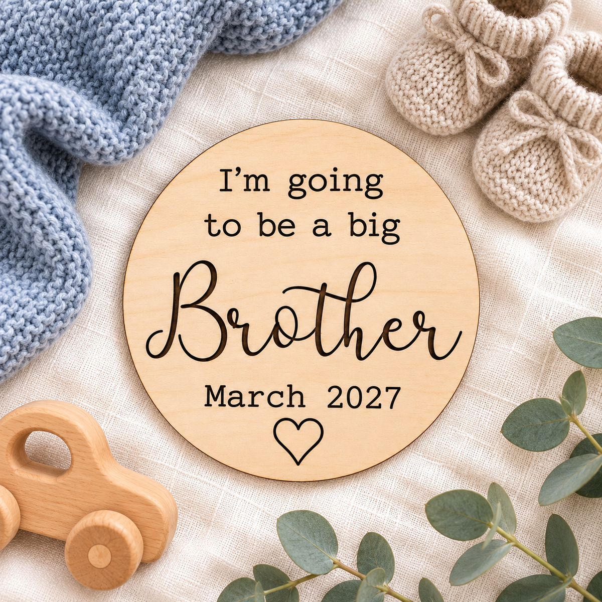 Big brother baby reveal sign styled with knitted baby booties and a blue blanket