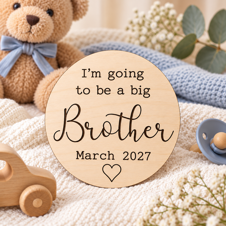 Wooden big brother sign with dark engraving beside a teddy bear on a cream blanket
