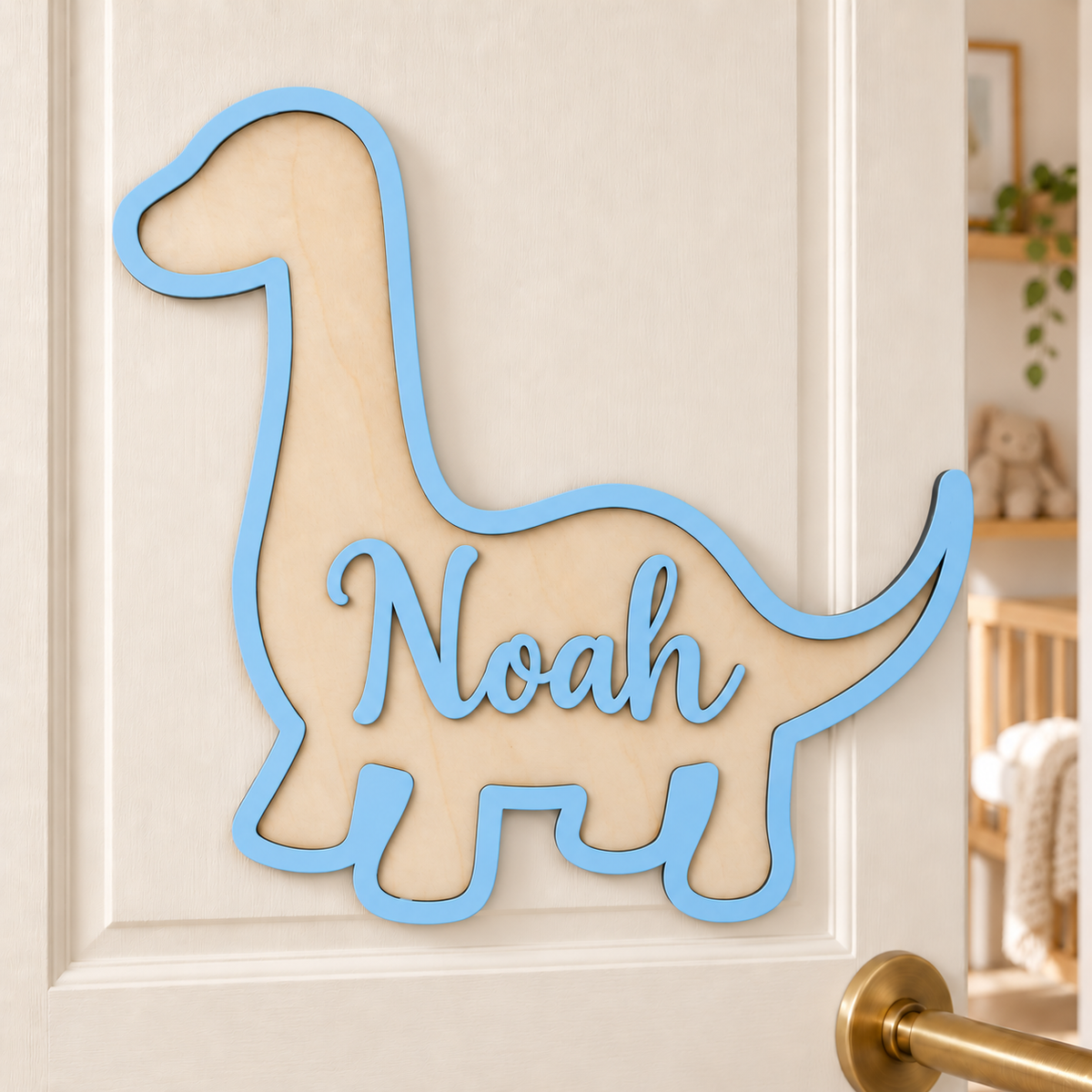 Pastel blue brachiosaurus name plaque with raised Noah lettering on a cream bedroom door