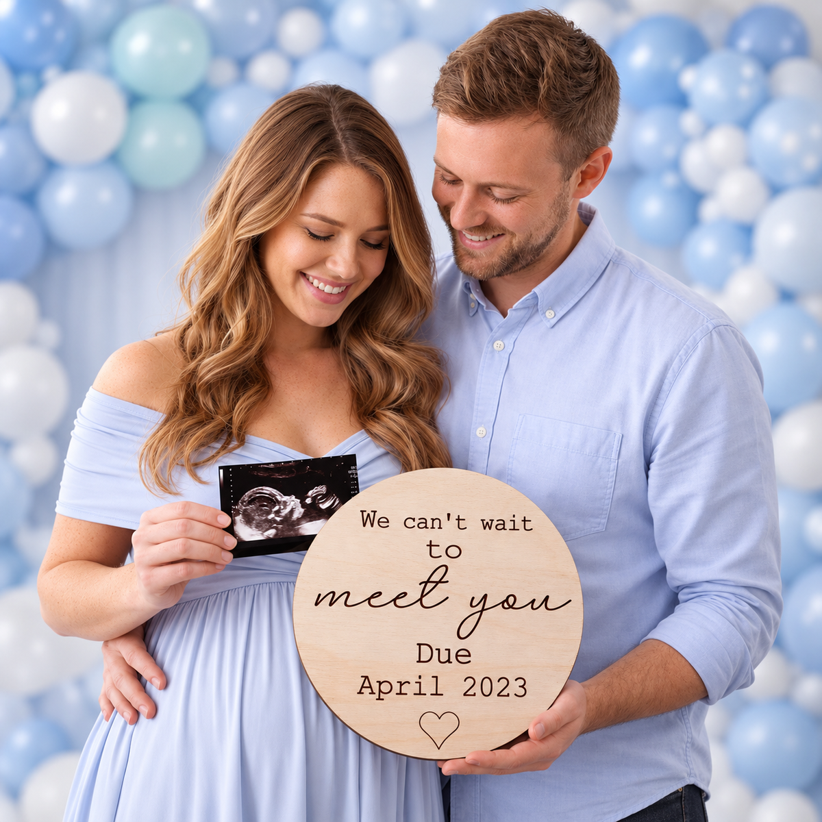 Expectant parents holding a personalised Can't Wait to Meet You wooden due date plaque beside an ultrasound photo.