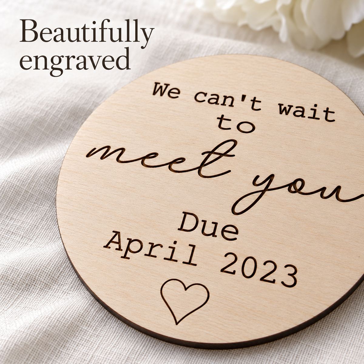 Close-up of dark laser engraved lettering, heart detail and natural birch wood grain on the due date plaque.
