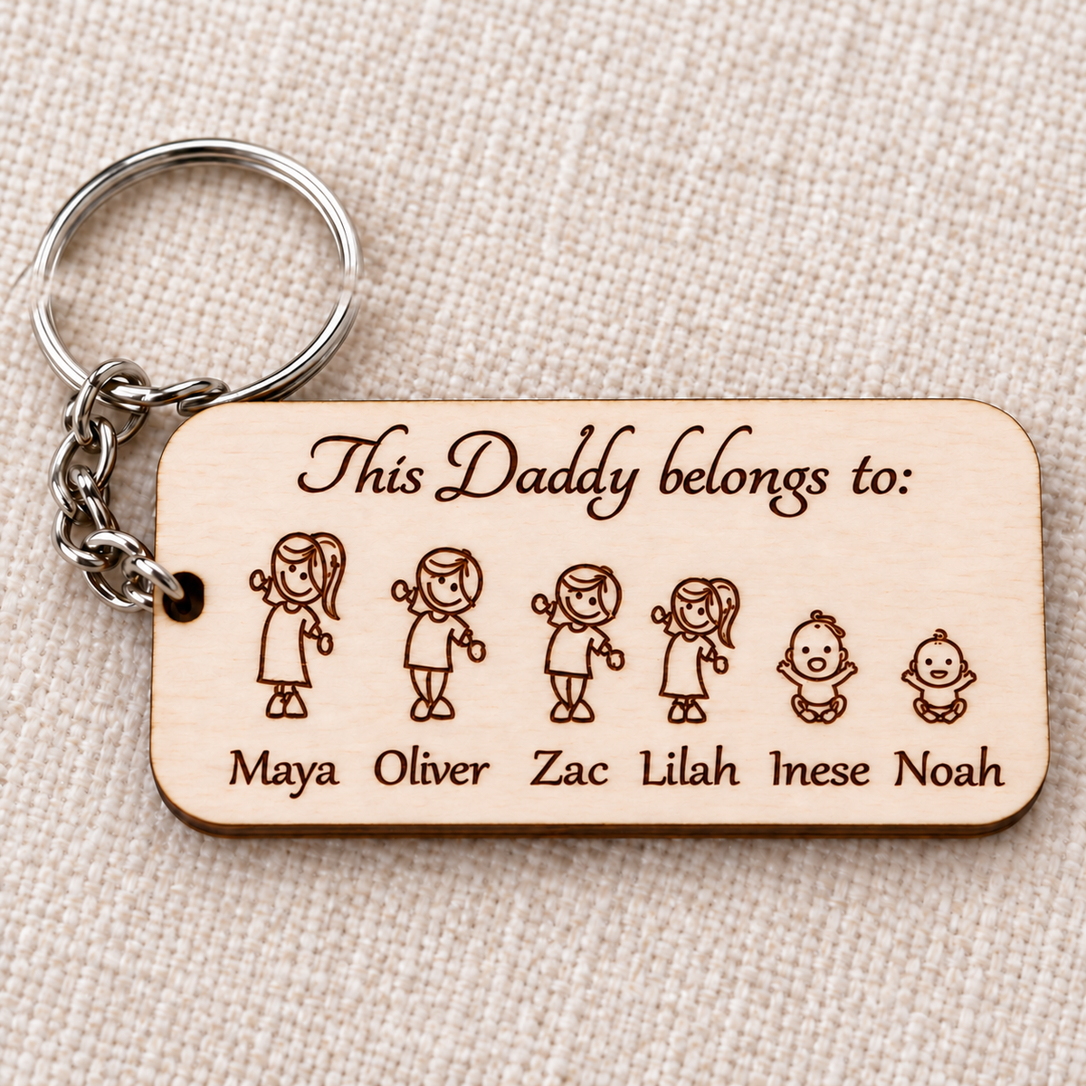 Close-up of the wooden Daddy keyring showing engraved characters, children's names and metal ring