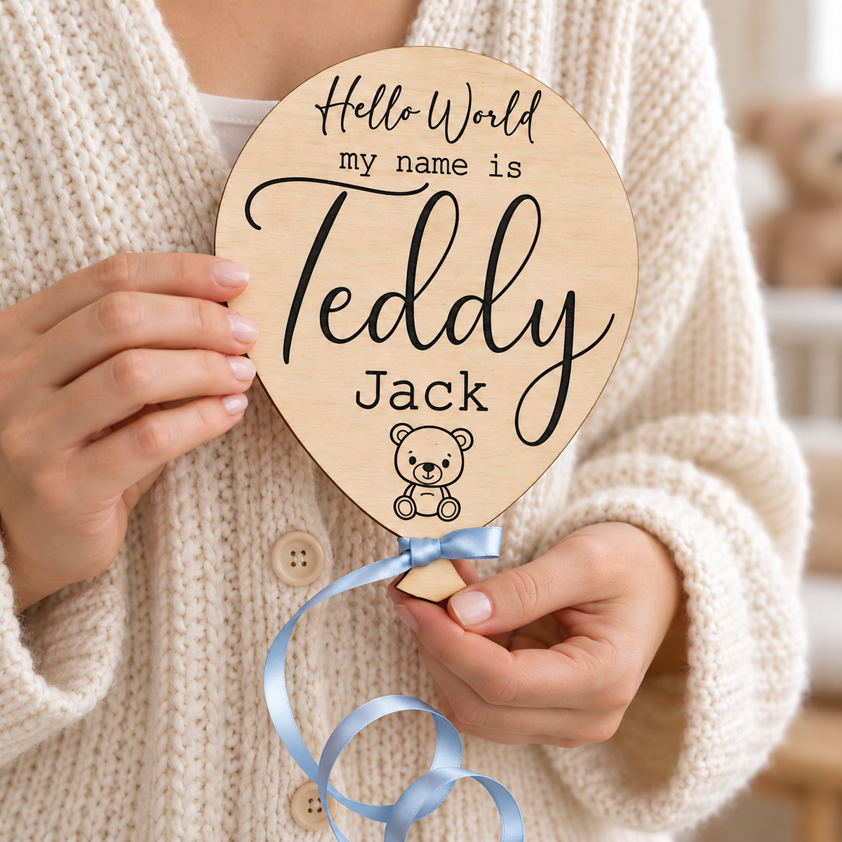 Personalised teddy bear balloon plaque held in adult hands with blue satin ribbon
