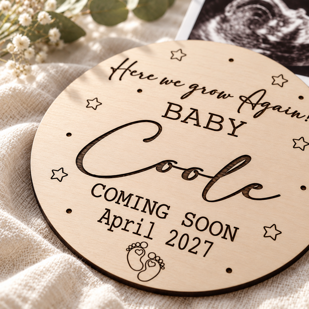 Close-up of dark laser engraving and the thin birch plywood edge of a pregnancy reveal plaque
