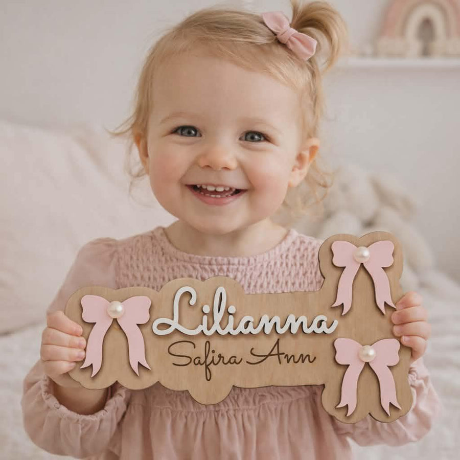 Smiling little girl holding a personalised bow name sign.