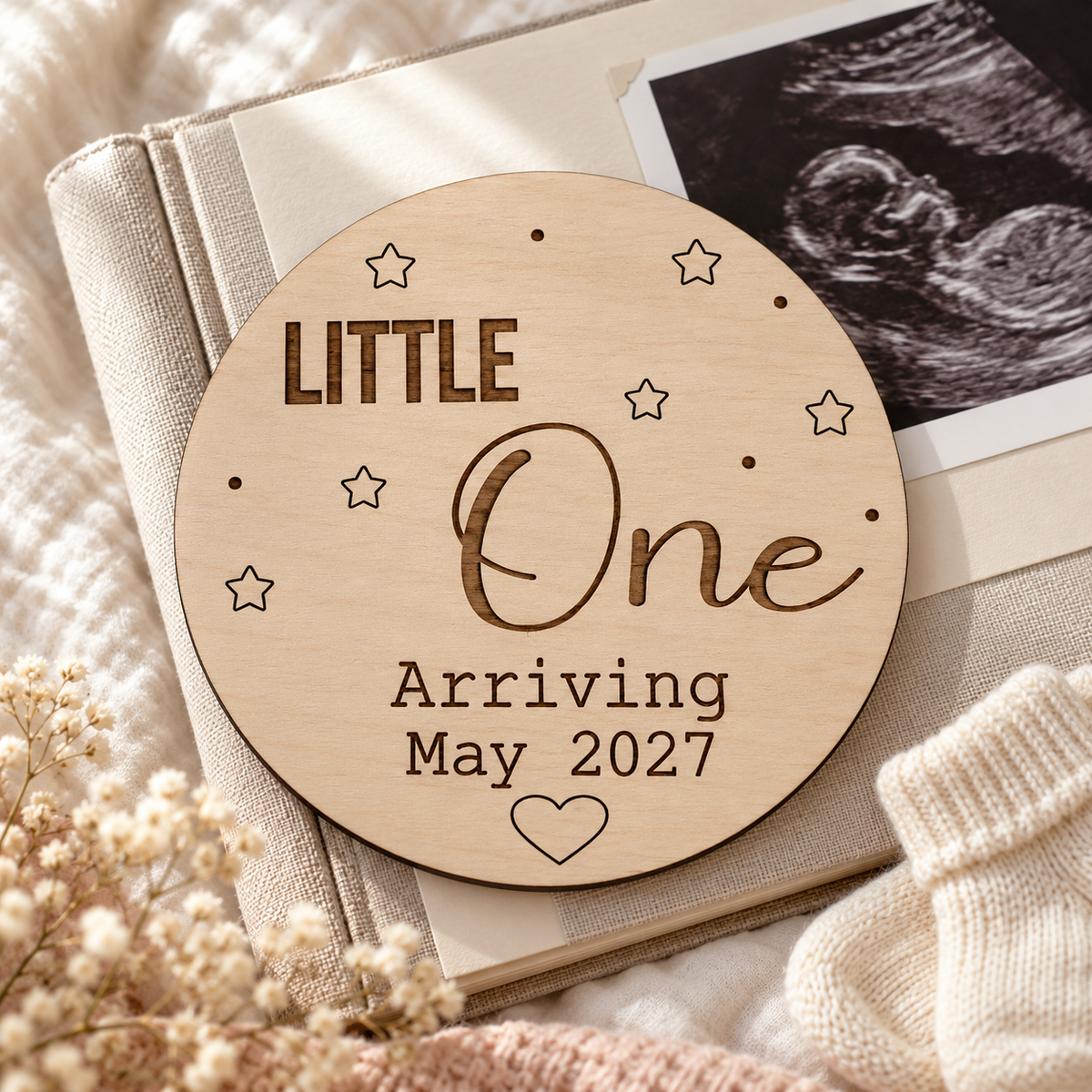 Personalised Little One pregnancy keepsake resting on a linen album beside an ultrasound and baby socks