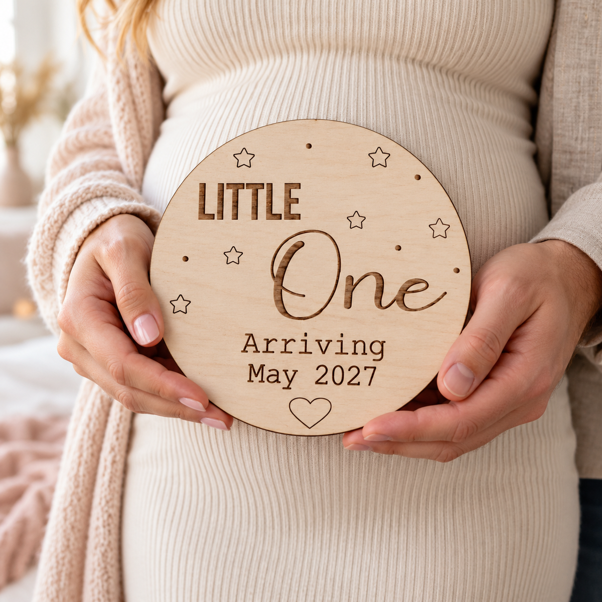 Expectant parents holding a personalised Little One Arriving wooden pregnancy announcement plaque
