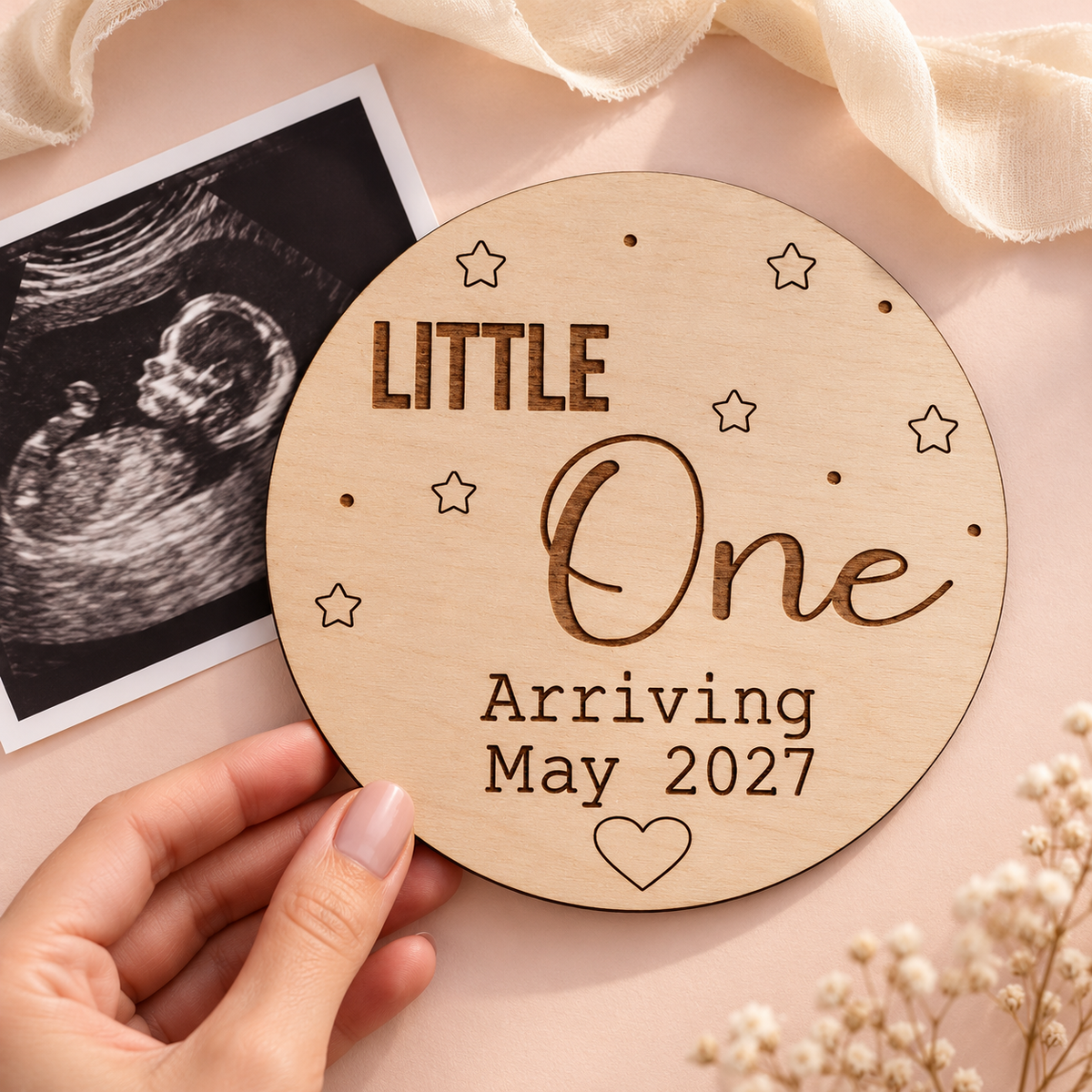 Little One Arriving May 2027 wooden sign beside an ultrasound on a pale blush background