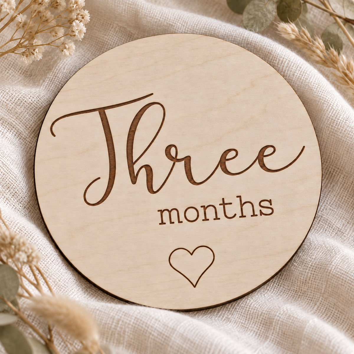 Close view of Three months script lettering, brown laser engraving and natural birch grain